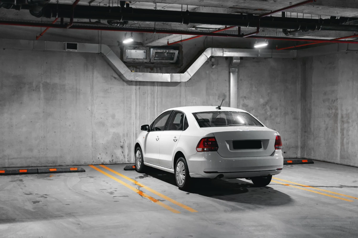 A white car parked in a reinforced concrete underground car park
